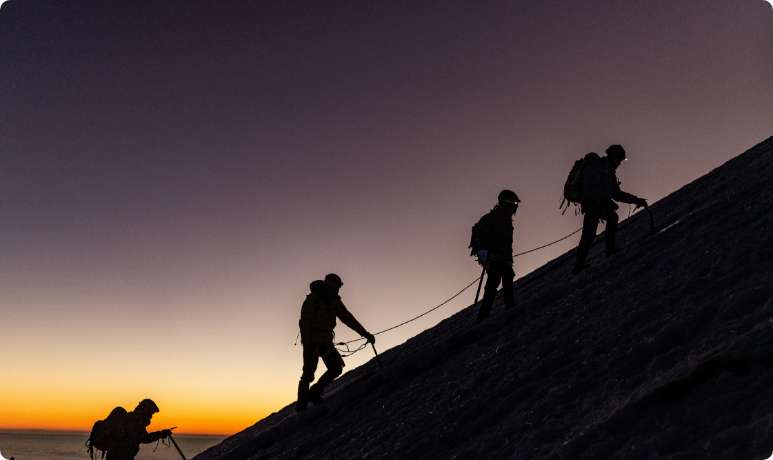 Scalatori sulla montagna davanti un tramonto